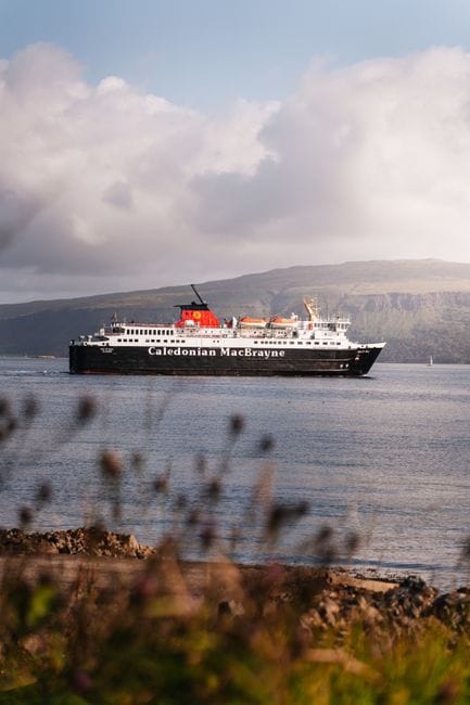 Caledonian MacBrayne ferry cruising through serene waters in Écosse, UK, with picturesque landscape.