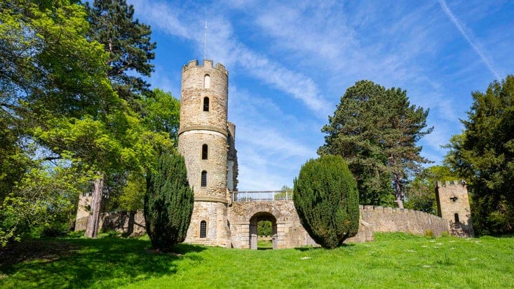 The exterior of Stainborough Castle, with a round tower and archway, at Wentworth Castle Gardens on a sunny day